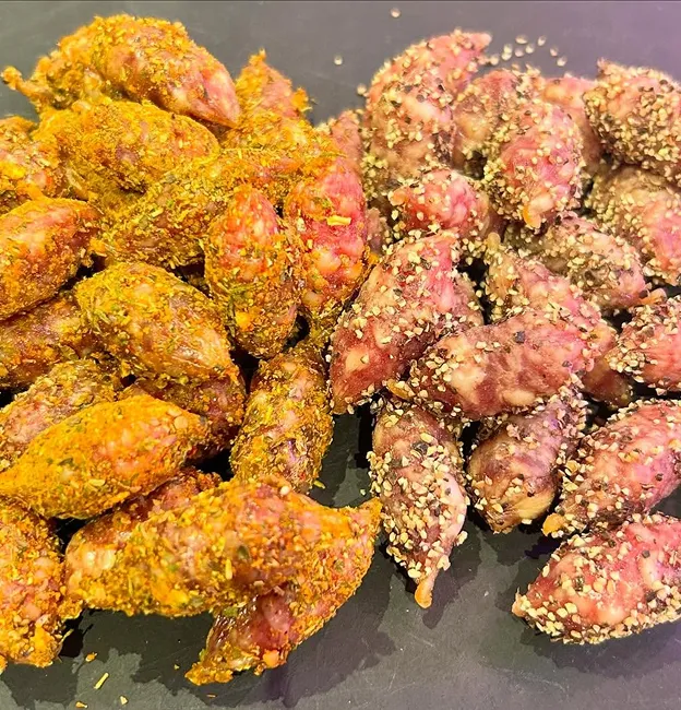 Petites saucisses assaisonnées, une moitié jaune épicé, l'autre poivrée foncée à Palaiseau en Essonne 91