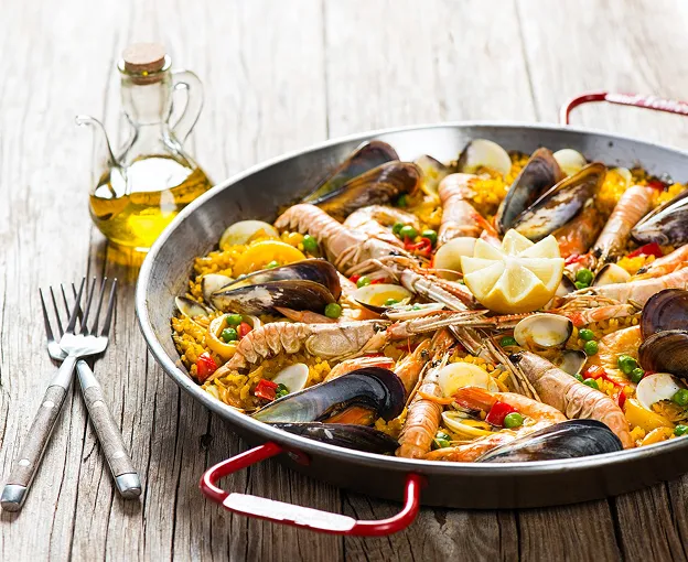 Paella aux fruits de mer garnie d'un quartier de citron dans une poêle à Palaiseau en Essonne 91