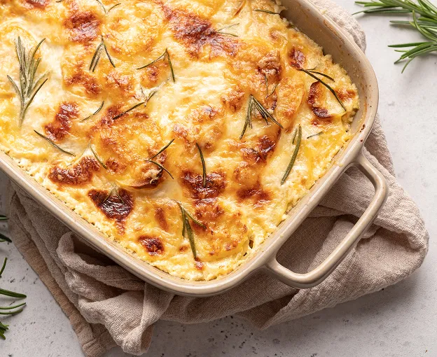 Gratin dauphinois doré et crémeux, garni de romarin frais dans un plat à four à Palaiseau en Essonne 91